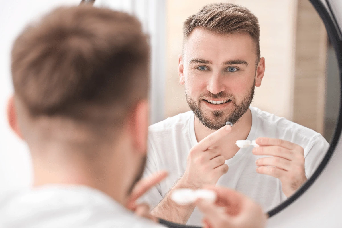 a man putting in a contact lens in the bathroom