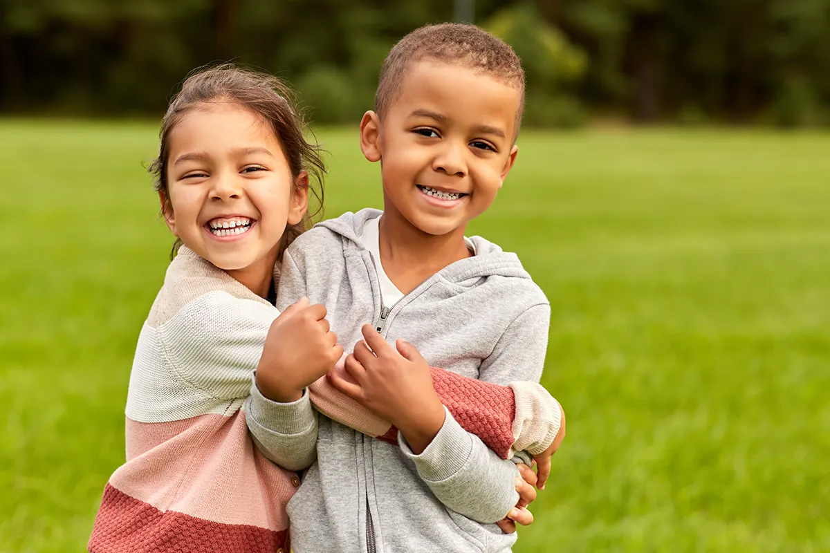 a little girl and boy hugging outside